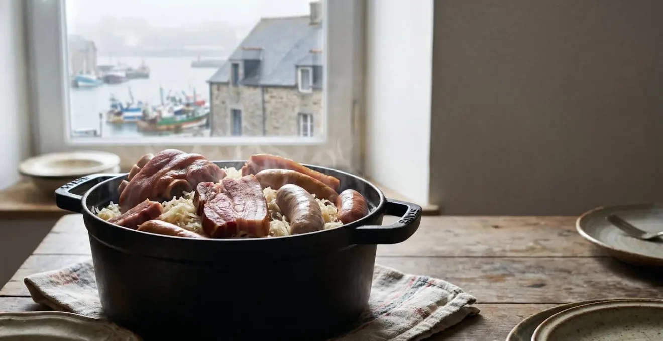 Plat genereux de choucroute et charcuteries fumees dresse sur une table en bois avec vue sur la rade de Brest en arriere-plan