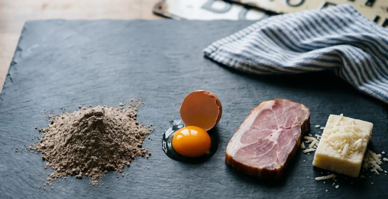 Composition élégante des quatre ingrédients essentiels d'une galette complète bretonne posés sur une table en ardoise